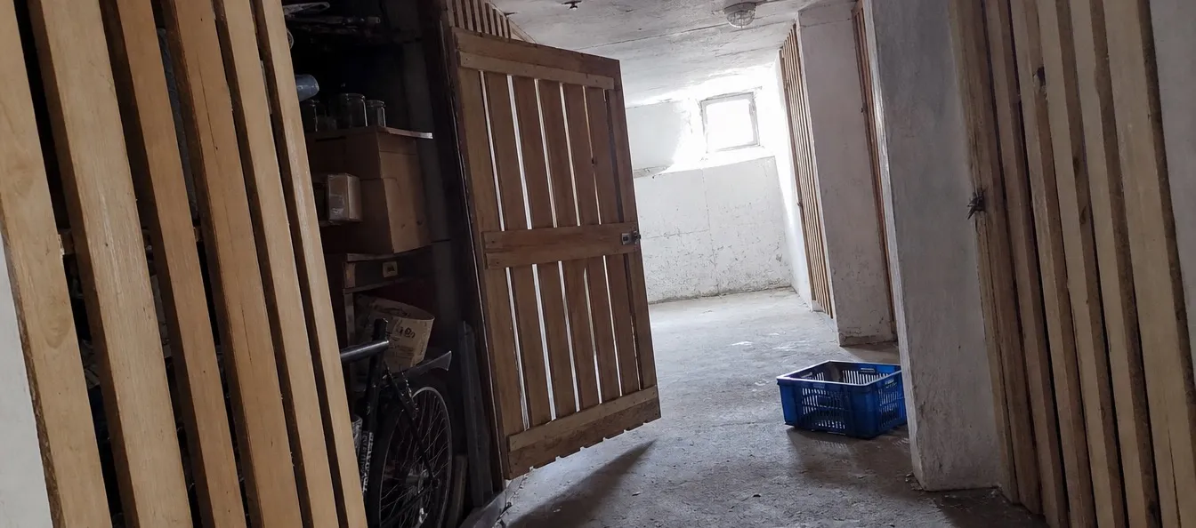 Kellergang mit Holzverschlägen, ein Abteil offen vor der Räumung